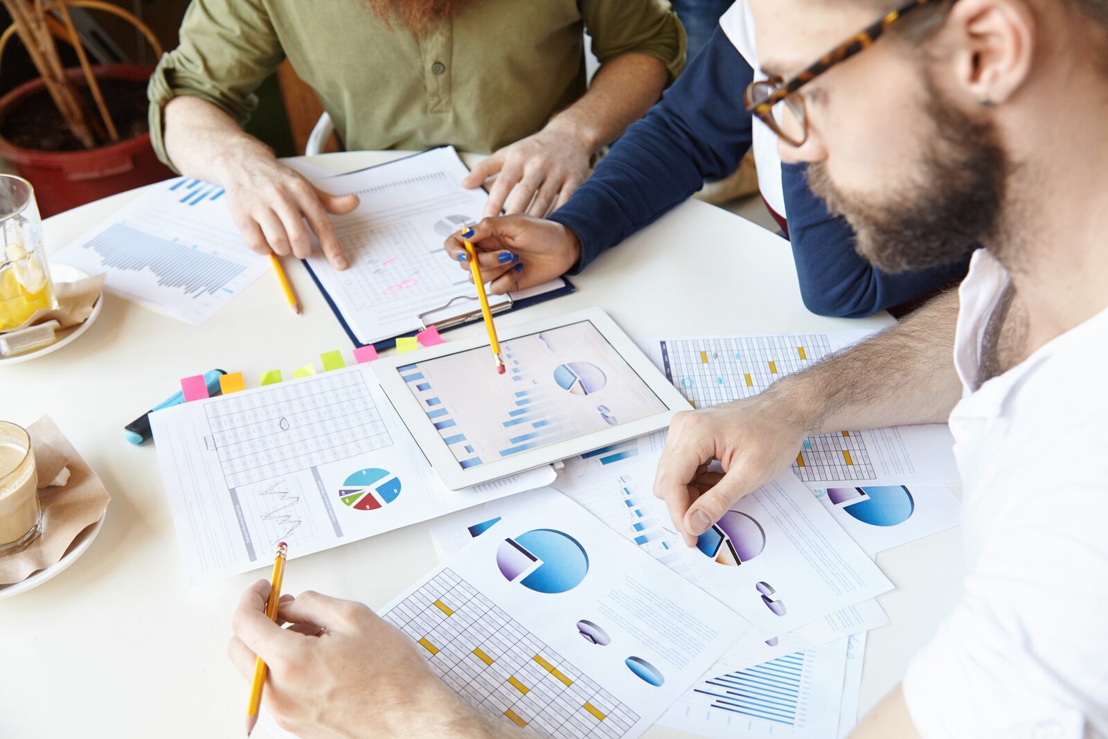 Four people seated around a table reviewing printed charts and charts on a tablet